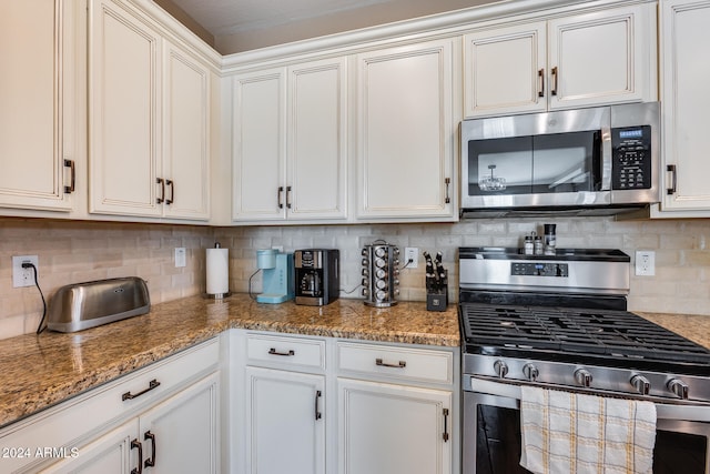 kitchen with backsplash, white cabinets, stainless steel appliances, and stone counters