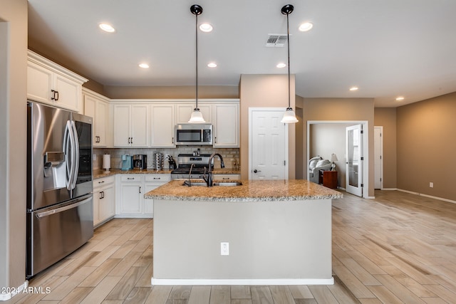 kitchen featuring sink, an island with sink, light hardwood / wood-style floors, and appliances with stainless steel finishes