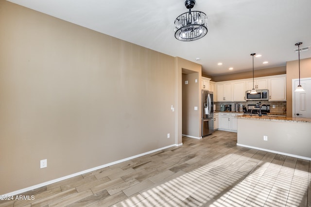 kitchen featuring tasteful backsplash, light stone counters, stainless steel appliances, decorative light fixtures, and white cabinets