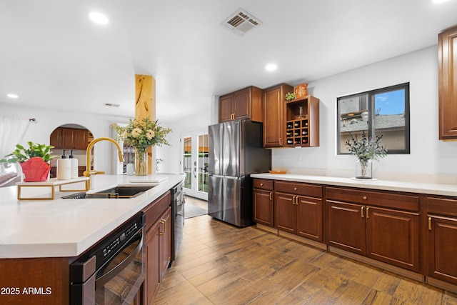 kitchen with dark wood-style flooring, visible vents, freestanding refrigerator, a sink, and dishwashing machine