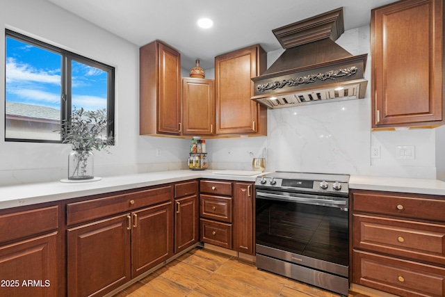 kitchen featuring electric range, custom range hood, light countertops, and backsplash