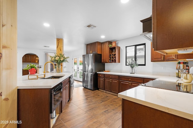 kitchen with open shelves, light countertops, visible vents, freestanding refrigerator, and a sink