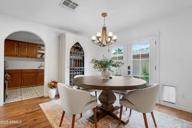 dining room featuring visible vents, a notable chandelier, baseboards, and wood finished floors