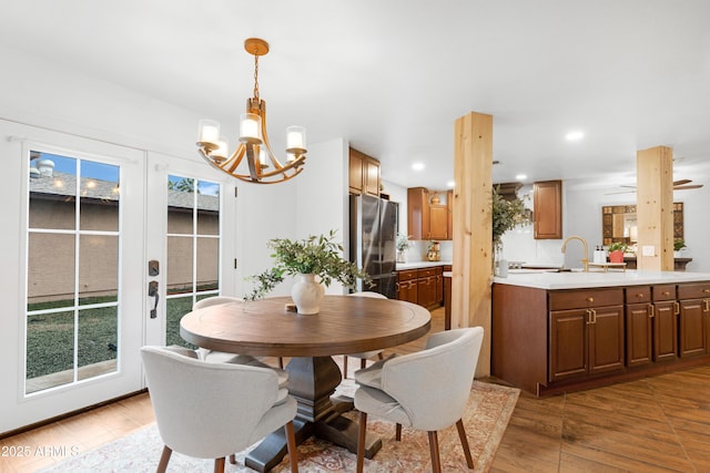 dining room featuring light wood finished floors, recessed lighting, ceiling fan with notable chandelier, and french doors