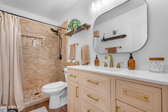 bathroom with a tile shower, vanity, wood finished floors, and toilet