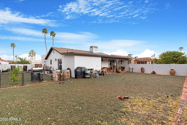 back of property featuring a yard, a fenced backyard, and stucco siding