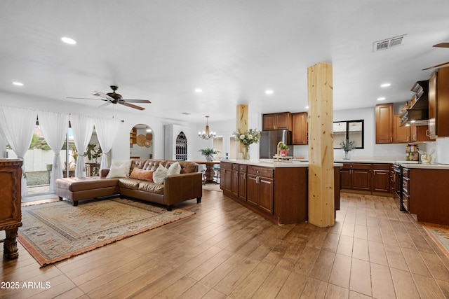 living room with light wood finished floors, ceiling fan with notable chandelier, visible vents, and recessed lighting