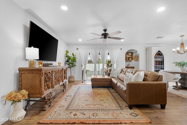 living room with recessed lighting, visible vents, arched walkways, wood finished floors, and ceiling fan with notable chandelier