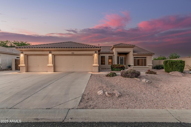 view of front of home featuring a tiled roof, an attached garage, stucco siding, and concrete driveway