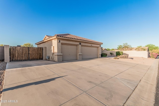 view of property exterior with concrete driveway, stucco siding, fence, a tiled roof, and a gate