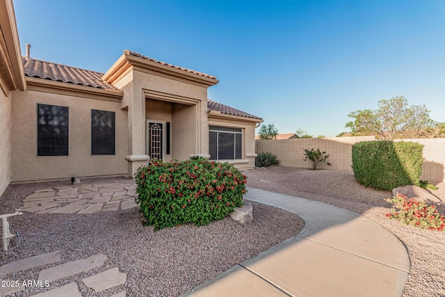 exterior space featuring a tiled roof, fence, stucco siding, and a patio area
