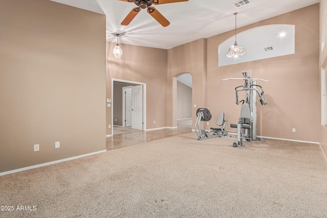 workout room with carpet, arched walkways, a ceiling fan, a high ceiling, and baseboards