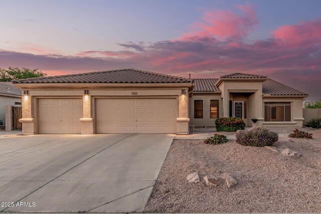mediterranean / spanish-style home featuring a garage, driveway, stucco siding, and a tile roof