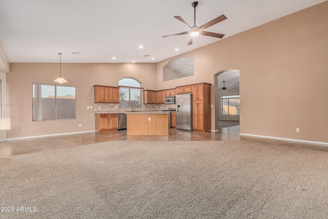 kitchen featuring baseboards, open floor plan, ceiling fan, high vaulted ceiling, and appliances with stainless steel finishes