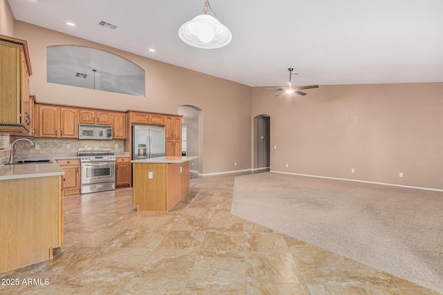 kitchen with arched walkways, visible vents, a kitchen island, a sink, and stainless steel appliances