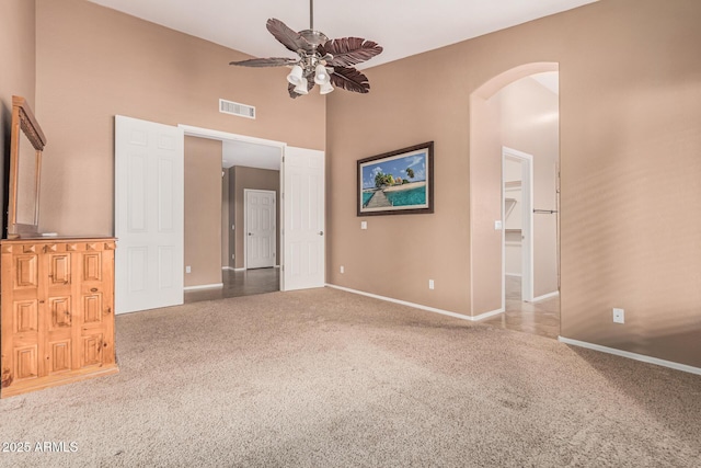 spare room with arched walkways, a ceiling fan, visible vents, carpet flooring, and baseboards