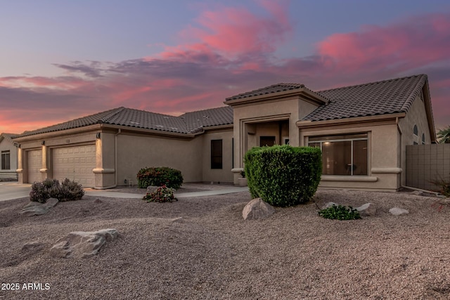 view of front facade featuring a garage, stucco siding, driveway, and a tile roof