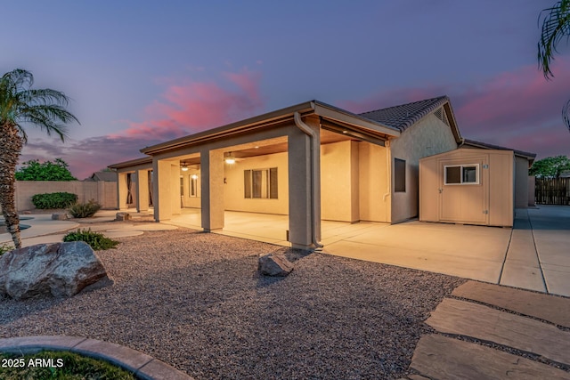 rear view of house featuring a patio, stucco siding, and fence