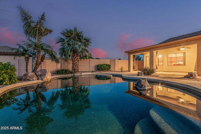 pool at dusk featuring a fenced backyard and a fenced in pool
