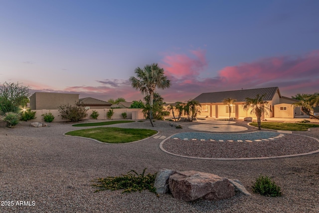 view of front of house featuring stucco siding, fence, curved driveway, and a tile roof