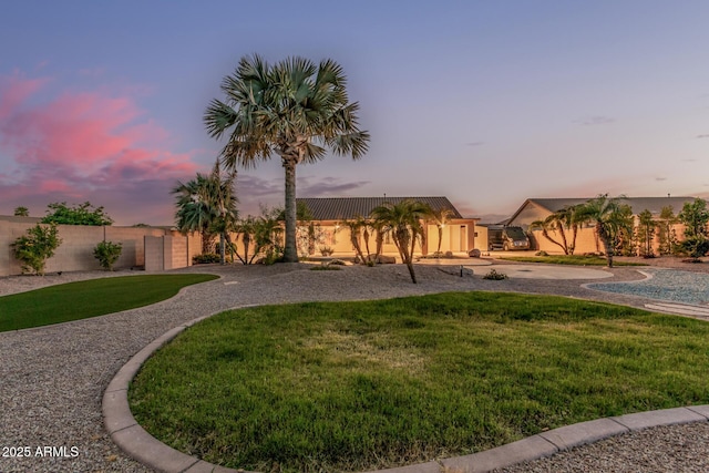 yard at dusk with fence and curved driveway