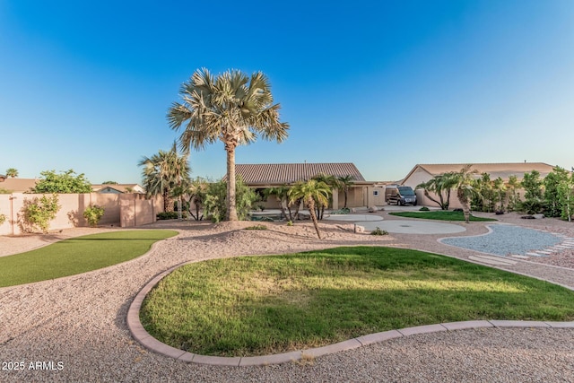 view of front facade featuring a front yard, stucco siding, fence, and a tile roof