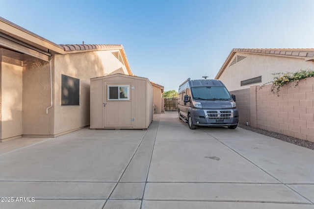 exterior space featuring stucco siding, a patio area, a storage shed, an outbuilding, and fence