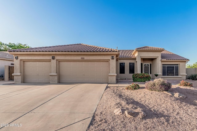 mediterranean / spanish-style house featuring a tiled roof, concrete driveway, stucco siding, and a garage