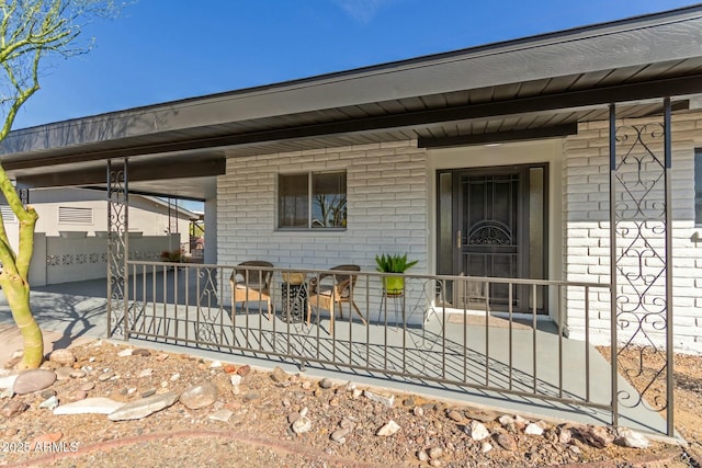 entrance to property with covered porch and brick siding