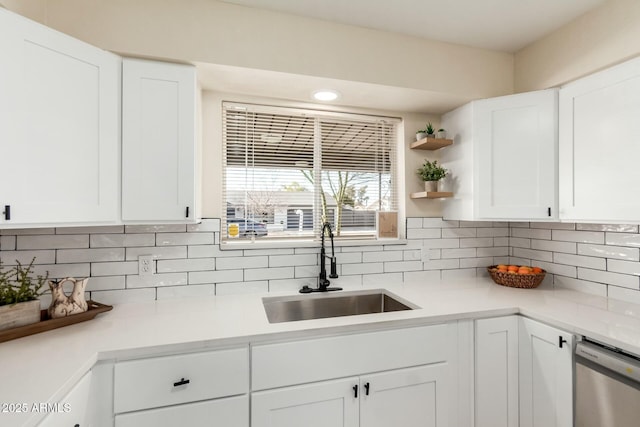 kitchen with light countertops, a sink, backsplash, and stainless steel dishwasher