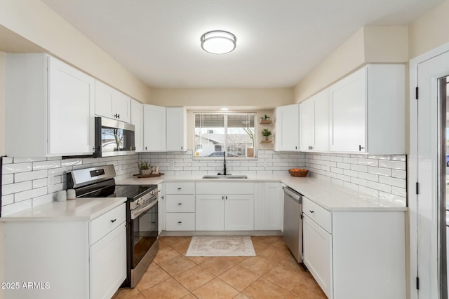 kitchen featuring appliances with stainless steel finishes, white cabinetry, a sink, and decorative backsplash