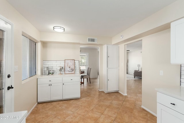 kitchen with light countertops, decorative backsplash, visible vents, and white cabinetry