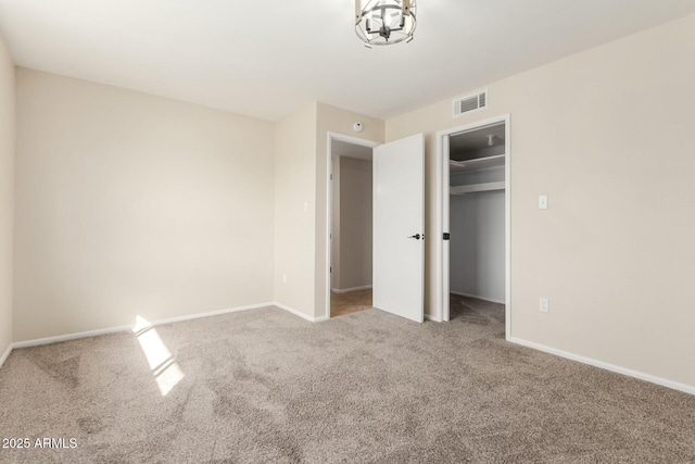 unfurnished bedroom featuring baseboards, visible vents, a spacious closet, and carpet flooring