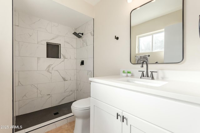 bathroom with toilet, tiled shower, and vanity