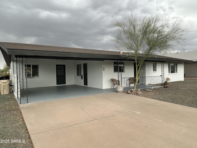 ranch-style home with an attached carport, concrete driveway, brick siding, and covered porch