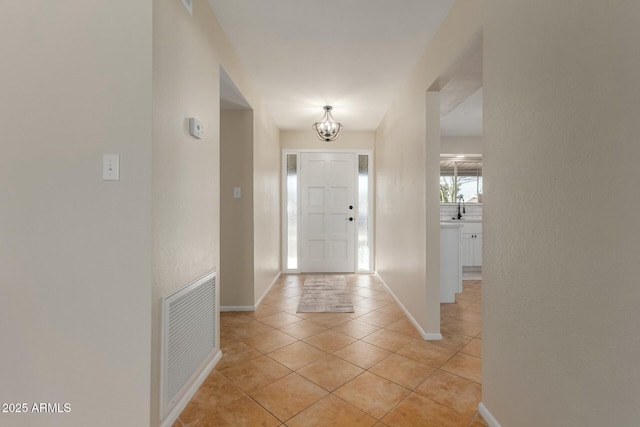 entrance foyer featuring visible vents, a notable chandelier, baseboards, and light tile patterned floors