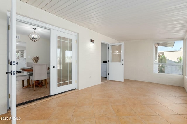 empty room with washer / dryer, french doors, light tile patterned flooring, and visible vents