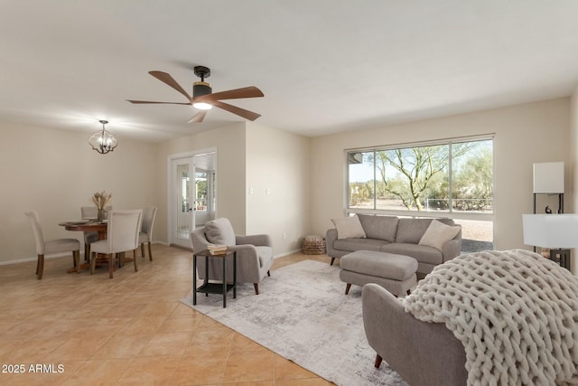 living room featuring light tile patterned floors, baseboards, and ceiling fan with notable chandelier