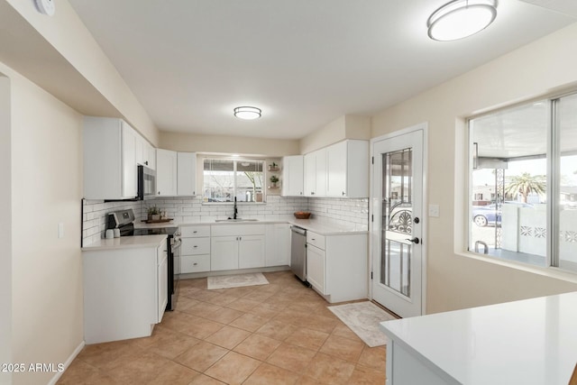 kitchen with stainless steel appliances, light countertops, a sink, and decorative backsplash