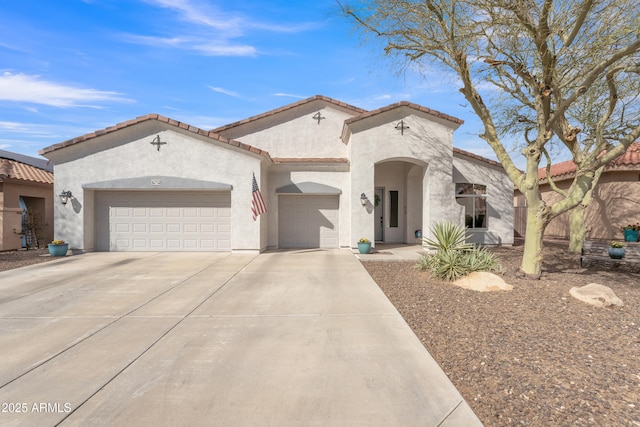 mediterranean / spanish-style house featuring a tiled roof, an attached garage, driveway, and stucco siding