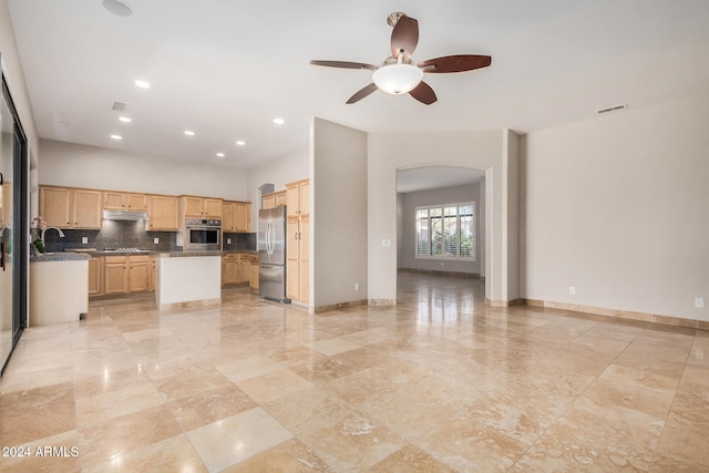 kitchen with appliances with stainless steel finishes, light brown cabinets, ceiling fan, backsplash, and a kitchen island