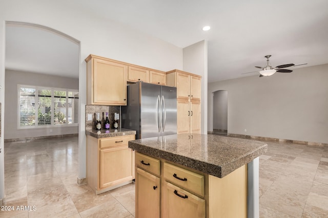 kitchen with light brown cabinetry, stainless steel refrigerator, ceiling fan, and a center island