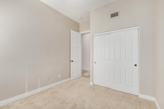 unfurnished bedroom with a closet and light colored carpet