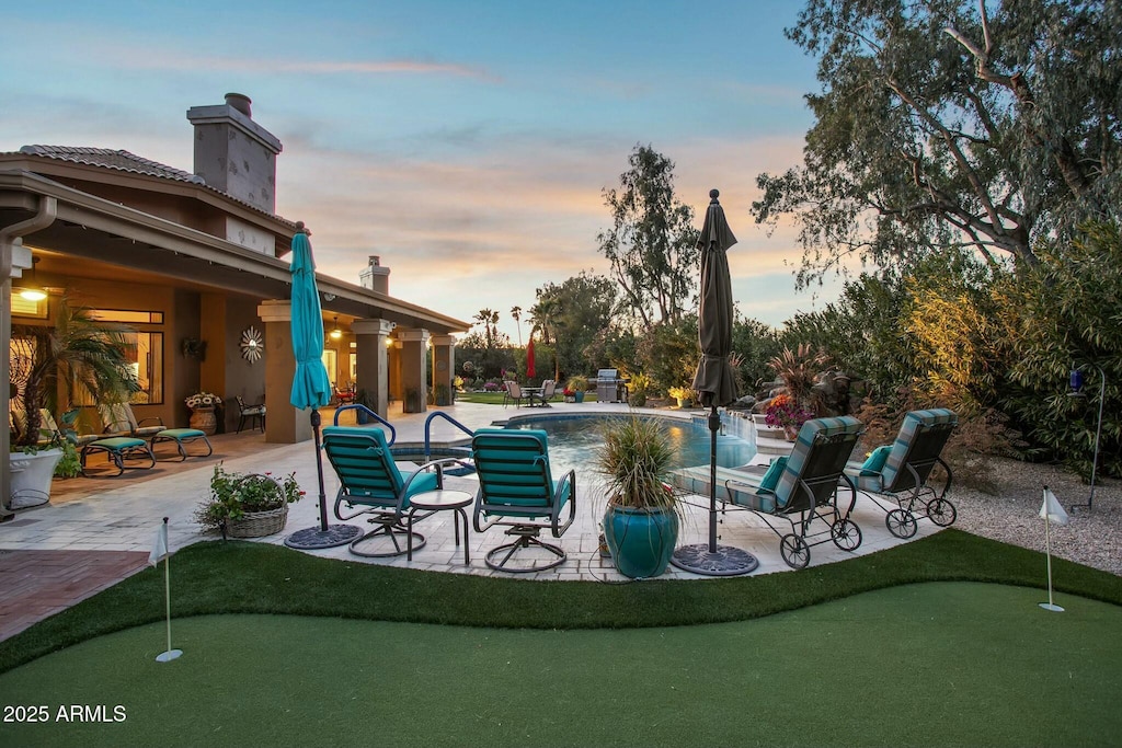 pool at dusk with a patio area