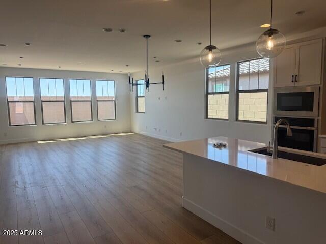 kitchen featuring a sink, appliances with stainless steel finishes, baseboards, open floor plan, and wood finished floors