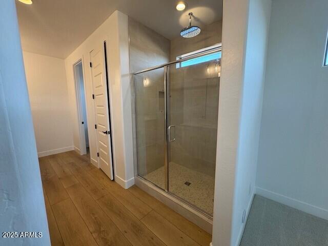 full bath with baseboards, wood finished floors, and a shower stall