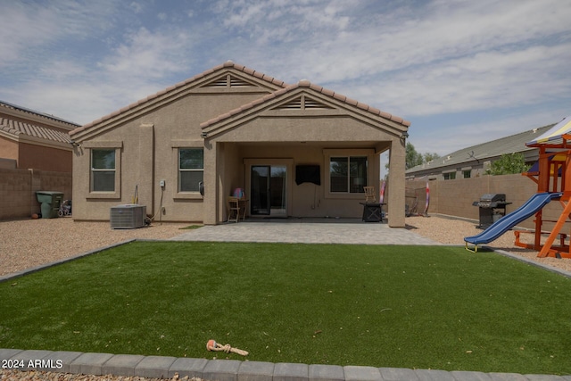 rear view of house with central AC unit, a yard, a playground, and a patio area