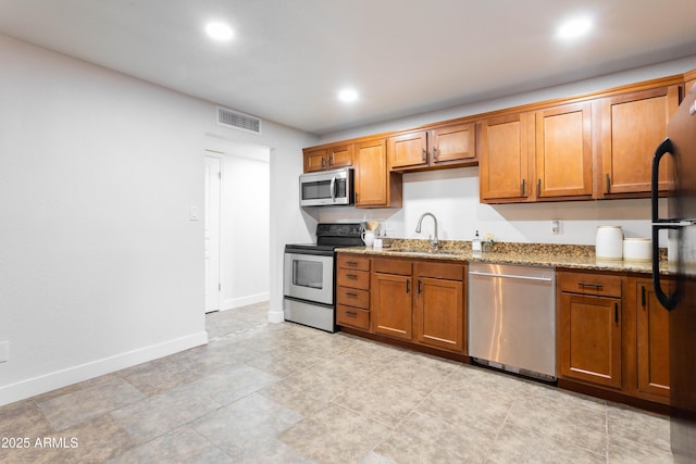 8021 W Hazelwood St, Phoenix, AZ 85033 - kitchen featuring stainless steel appliances, a sink, light stone counters, brown cabinetry, and recessed lighting
