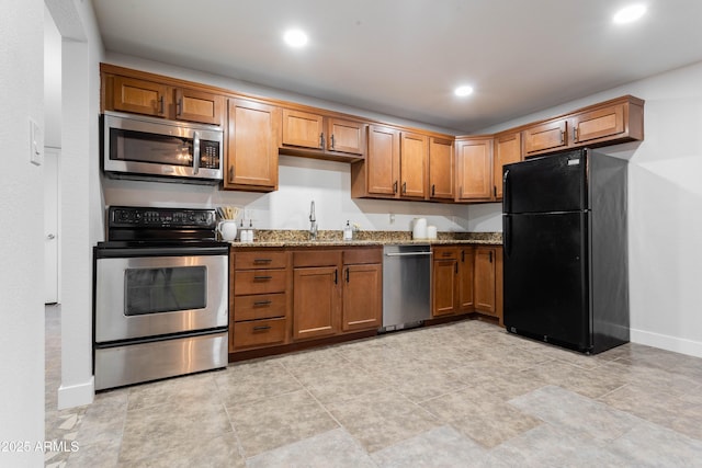 8021 W Hazelwood St, Phoenix, AZ 85033 - kitchen with stainless steel appliances, light stone counters, brown cabinetry, baseboards, and recessed lighting
