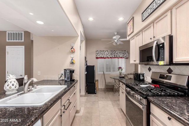 kitchen with sink, appliances with stainless steel finishes, ceiling fan, dark stone counters, and decorative backsplash